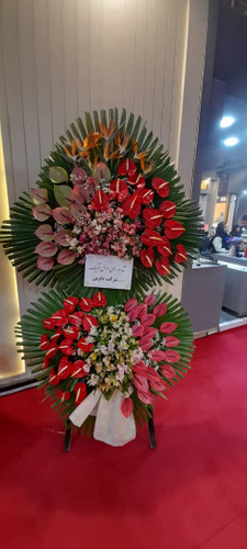 تاج گل تبریک افتتاحیه | با استفاده از گل های آنتریوم هلندی، استرزیا و آلسترومریا روی پایه چوبی در ارتفاع ۲.۵ متر